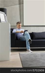 Full-length of Middle-aged man using tablet PC on sofa