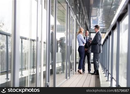 Full length of multi-ethnic business people discussing on office balcony