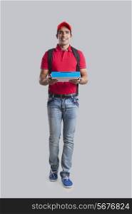 Full length of pizza delivery man against gray background