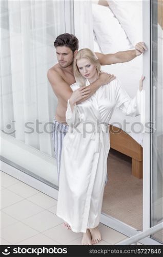 Full length of romantic young couple spending quality time at balcony doorway