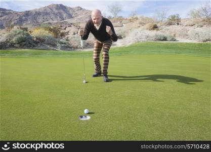 Full length of senior male golfer celebrating a putt at golf course