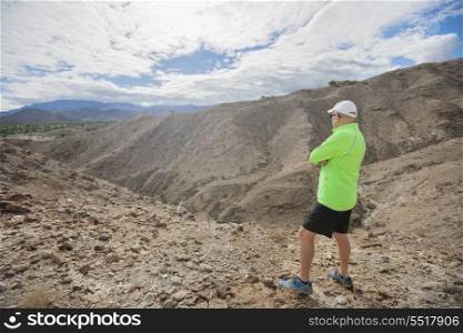 Full length of senior man looking at view while standing on rock