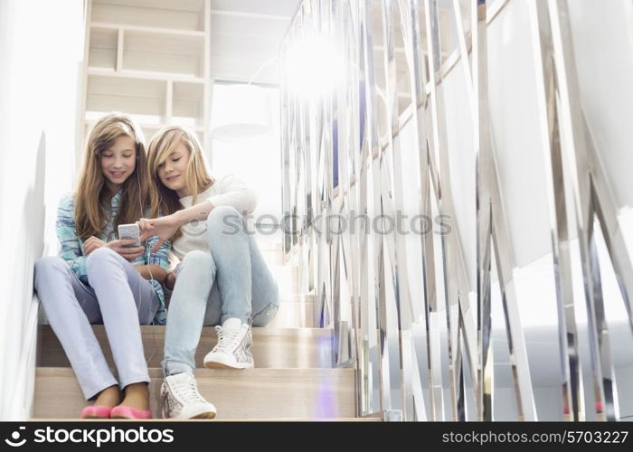 Full-length of sisters listening to music on stairway