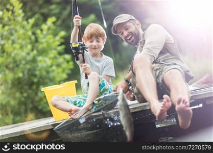 Full length of smiling father and son catching fish in butterfly fishing net
