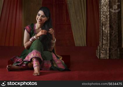 Full length of smiling Indian bride sitting while looking away