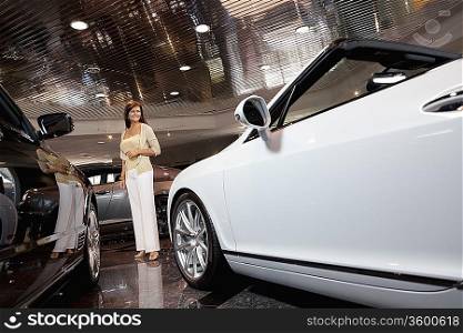 Full-length of smiling woman standing in car showroom