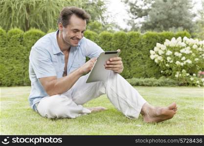 Full length of smiling young man using digital tablet in park