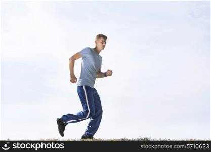 Full length of sporty man jogging against sky