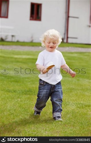 Full length of sweet little boy holding gardening tool in garden and walking