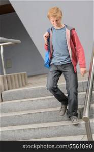 Full length of teenage student walking down university stairs