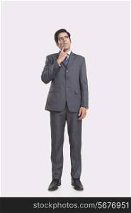 Full length of thoughtful businessman over gray background