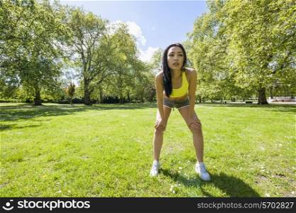 Full length of tired fit woman taking a break while exercising in park