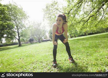 Full length of tired fit woman taking break while exercising in park