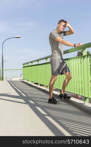 Full length of tired man wiping sweat on bridge after jogging