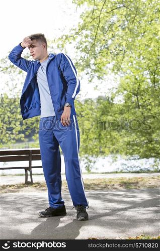 Full length of tired young jogger standing on path in park