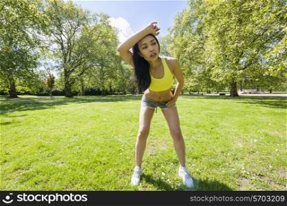 Full length of tired young woman looking away while exercising in park