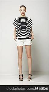 Full Length of Trendy Woman in Shorts and Grey Striped Shirt. Casual Modern Collection