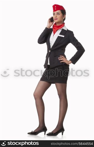 Full length of young airhostess using mobile phone while looking up over white background