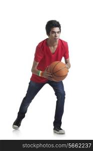 Full length of young boy ready to throw basketball over white background