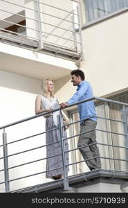 Full length of young business couple conversing at hotel balcony