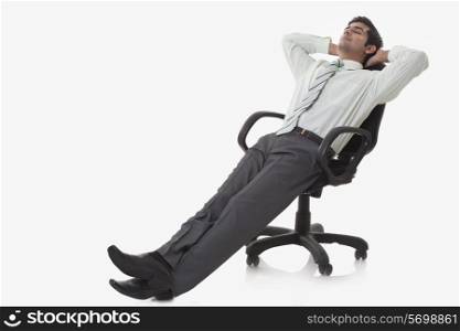Full length of young businessman relaxing on chair