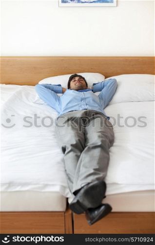 Full length of young businessman sleeping in hotel room