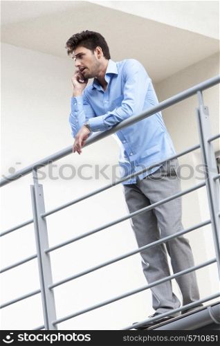 Full length of young businessman using cell phone at hotel balcony