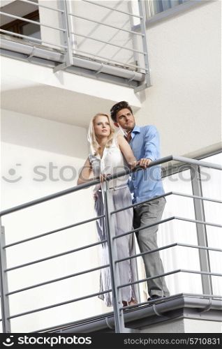Full length of young couple looking away while standing at hotel balcony