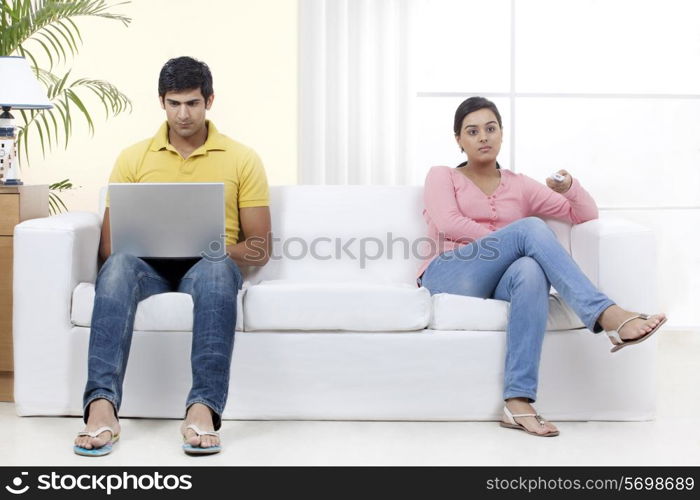 Full length of young couple sitting on sofa