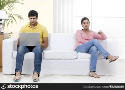 Full length of young couple sitting on sofa