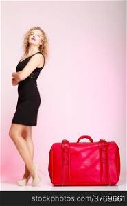Full length of young elegant lady in voyage, traveler woman with old red suitcase luggage bag on pink background. Travel theme