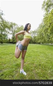 Full length of young fit woman performing stretching exercise at park