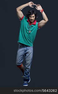 Full length of young Indian man with arms raised against black background