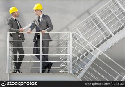 Full length of young male architect discussing on stairway