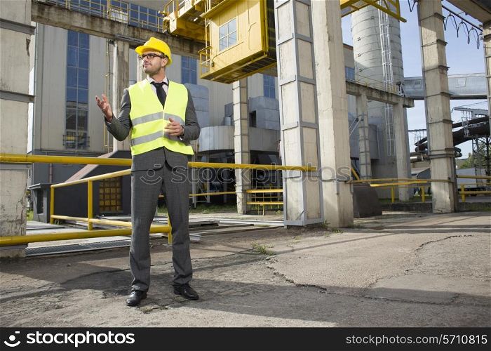 Full length of young male architect gesturing outside industry