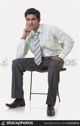 Full length of young male executive contemplating over white background
