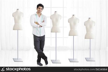 Full length of young male fashion designer standing by mannequin at studio