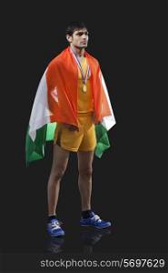 Full length of young male medalist with Indian flag looking away against black background