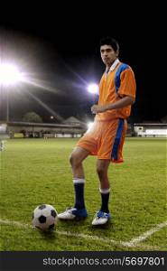 Full length of young male player kicking soccer ball on field