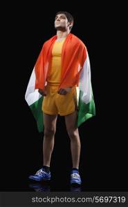 Full length of young male runner with Indian flag standing against black background