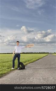 Full length of young man holding anywhere sign on empty road
