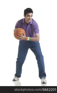 Full length of young man looking away while holding basketball over white background