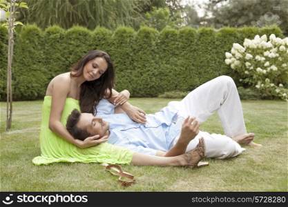 Full length of young man lying on woman&rsquo;s lap in park