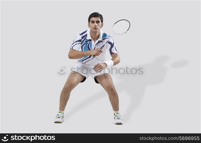 Full length of young man playing badminton isolated over white background