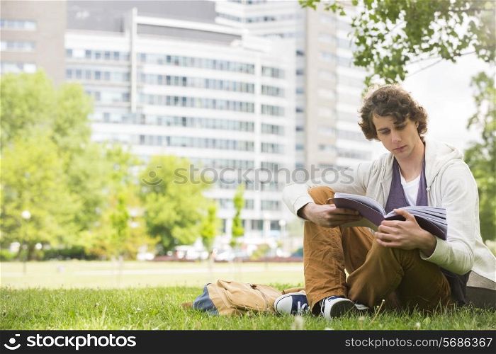 Full length of young man reading book on college campus