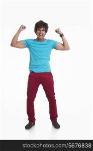 Full length of young man screaming while flexing muscles over white background