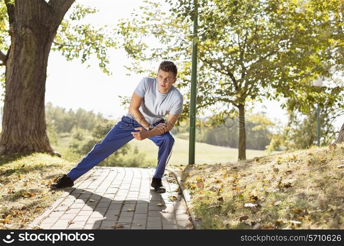 Full length of young man stretching on path in park
