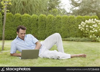Full length of young man using laptop while reclining in park