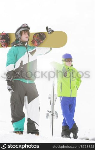 Full length of young men with snowboards in snow