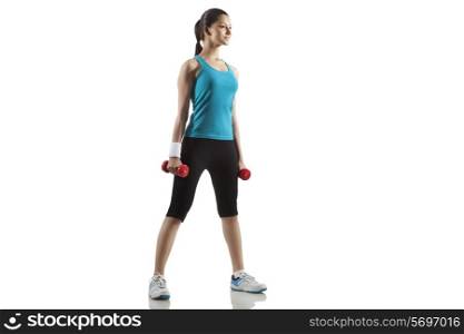 Full length of young woman holding dumbbells isolated over white background
